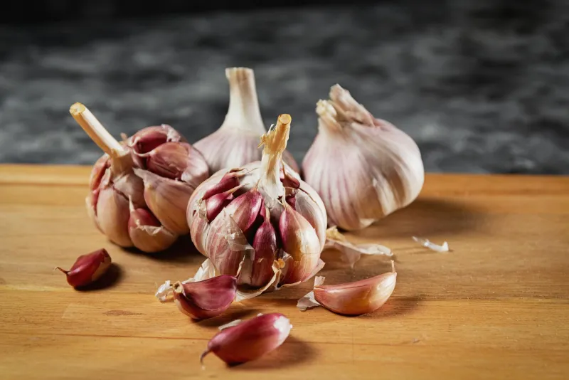 Garlic oil softgels and fresh garlic cloves on a wooden surface