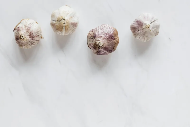 Fresh garlic bulbs and a bottle of garlic oil on a table