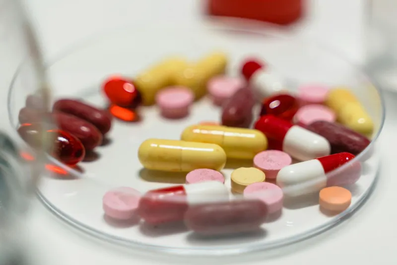 Multivitamiini kapslid laual koos erinevate toitudega, mis illustreerivad koostoimeid