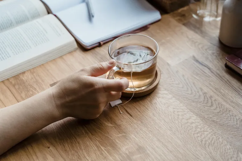 Cup of green tea alongside L-theanine capsules on a calm desk