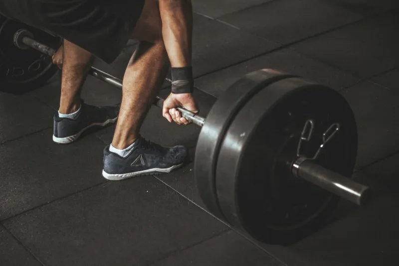 Creatine powder in a measuring scoop next to gym equipment