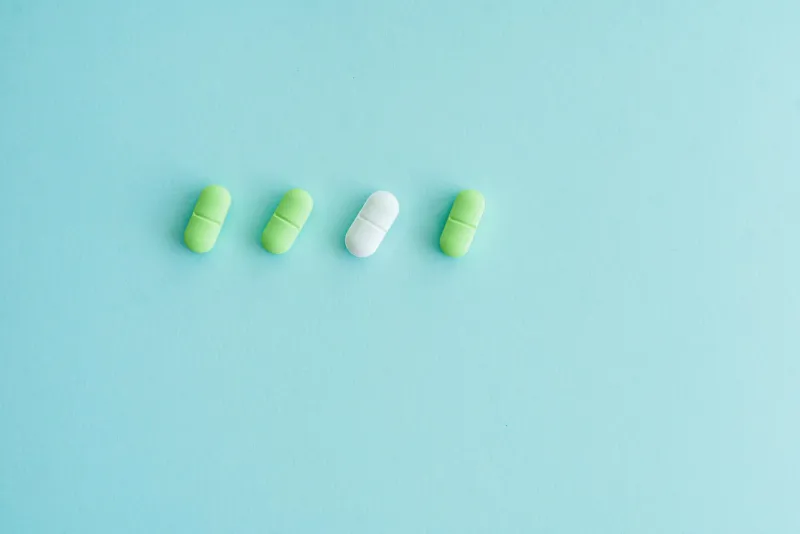 Person sleeping peacefully in a dark bedroom with melatonin capsules on the nightstand