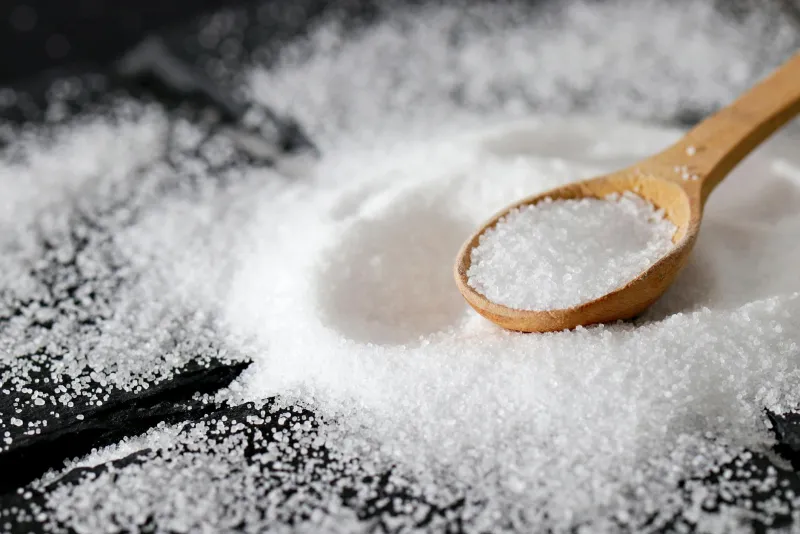 Inositol supplement powder with a glass of water alongside fruits and nuts on a table
